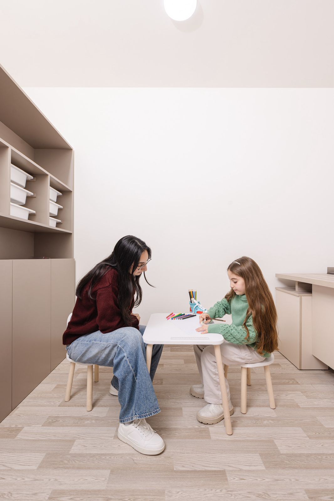 Therapist sitting with a child in a calm, cozy therapy room with soft lighting and comfortable seating
