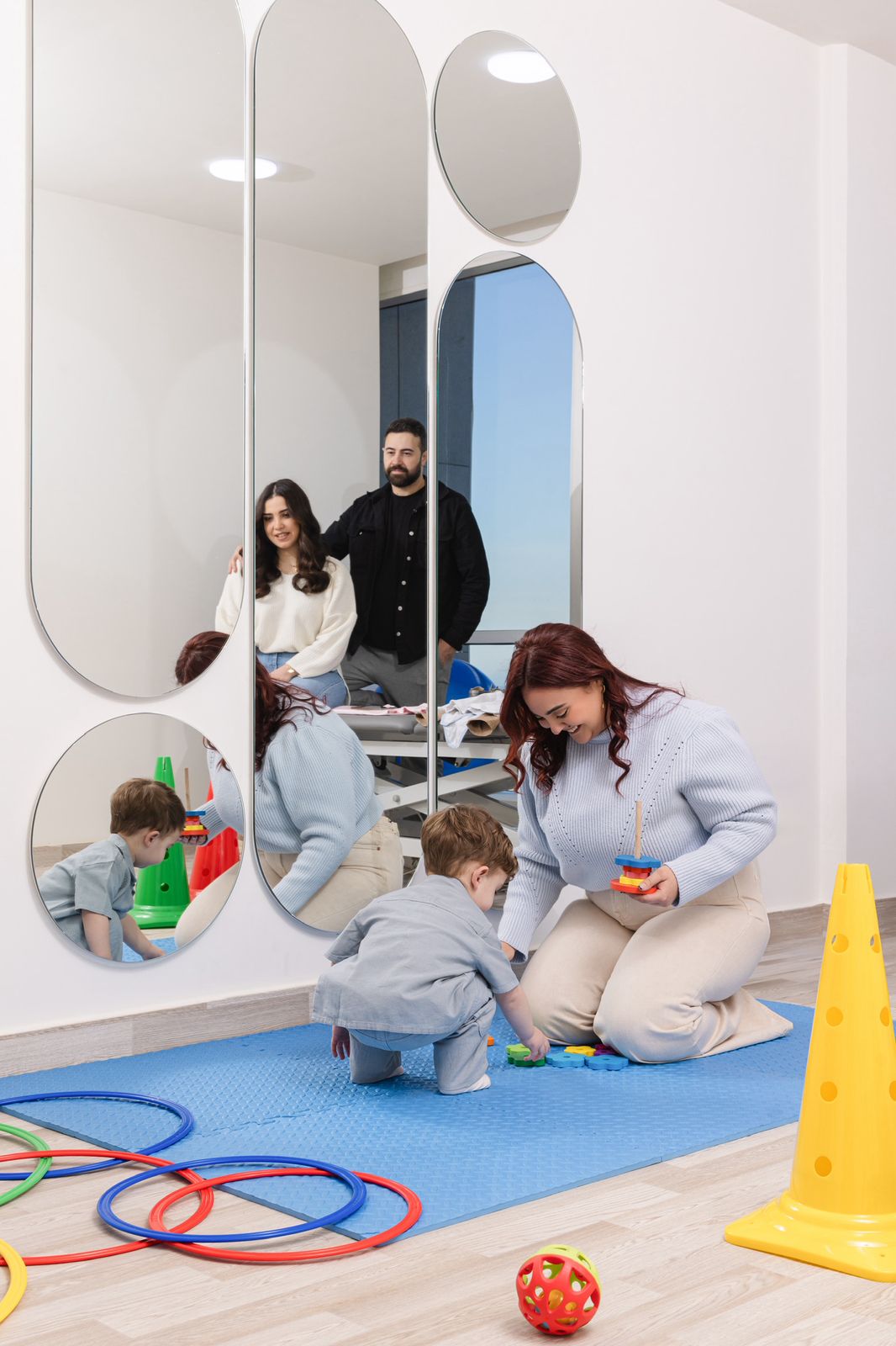 Physical therapist helping a toddler practice walking and balance exercises in a bright therapy room