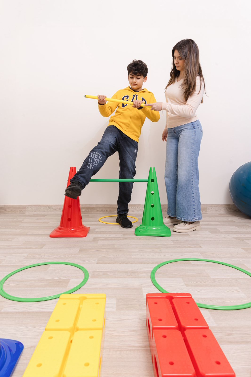 Child playing with sensory materials and movement activities guided by a therapist in a colorful room