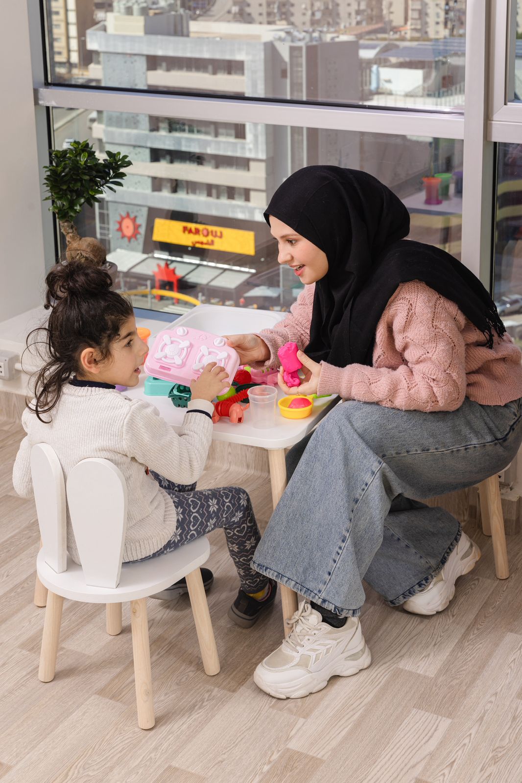 Speech therapist working with a young child using colorful communication cards on a table
